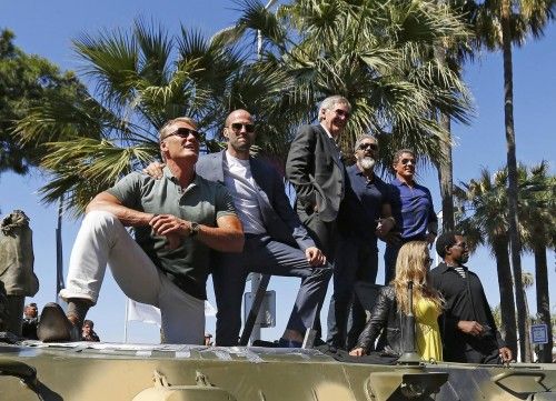 Cast members Lundgren, Statham, Ford, Gibson, Rousey, Stallone and Snipes pose on a tank as they arrive on the Croisette to promote the film "The Expendables 3" during the 67th Cannes Film Festival in Cannes