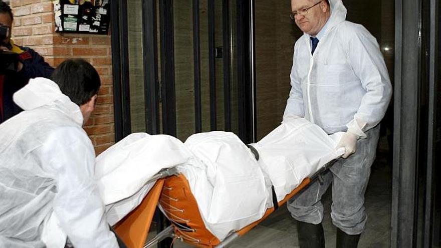 Empleados del Instituto de Medicina Legal trasladan el cuerpo sin vida de la mujer fallecida hoy, junto a su marido, ambos de avanzada edad, a causa de un incendio que se declaró en su vivienda, ubicada en un barrio céntrico de la capital murciana.
