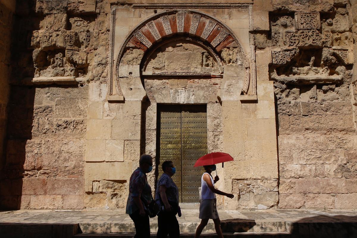 Varias personas pasean junto a la Mezquita-Catedral de Córdoba en hora punta de calor.