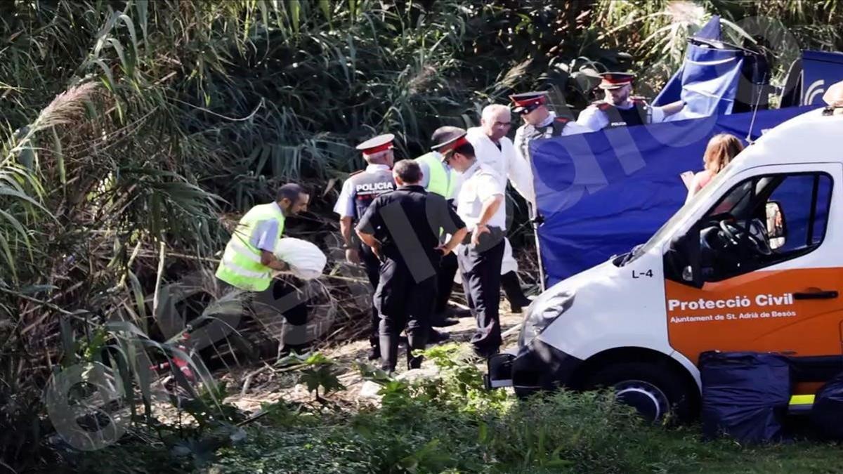 Un miembro de la comitiva judicial sostiene el cuerpo sin vida del bebé arrojado al río Besòs.