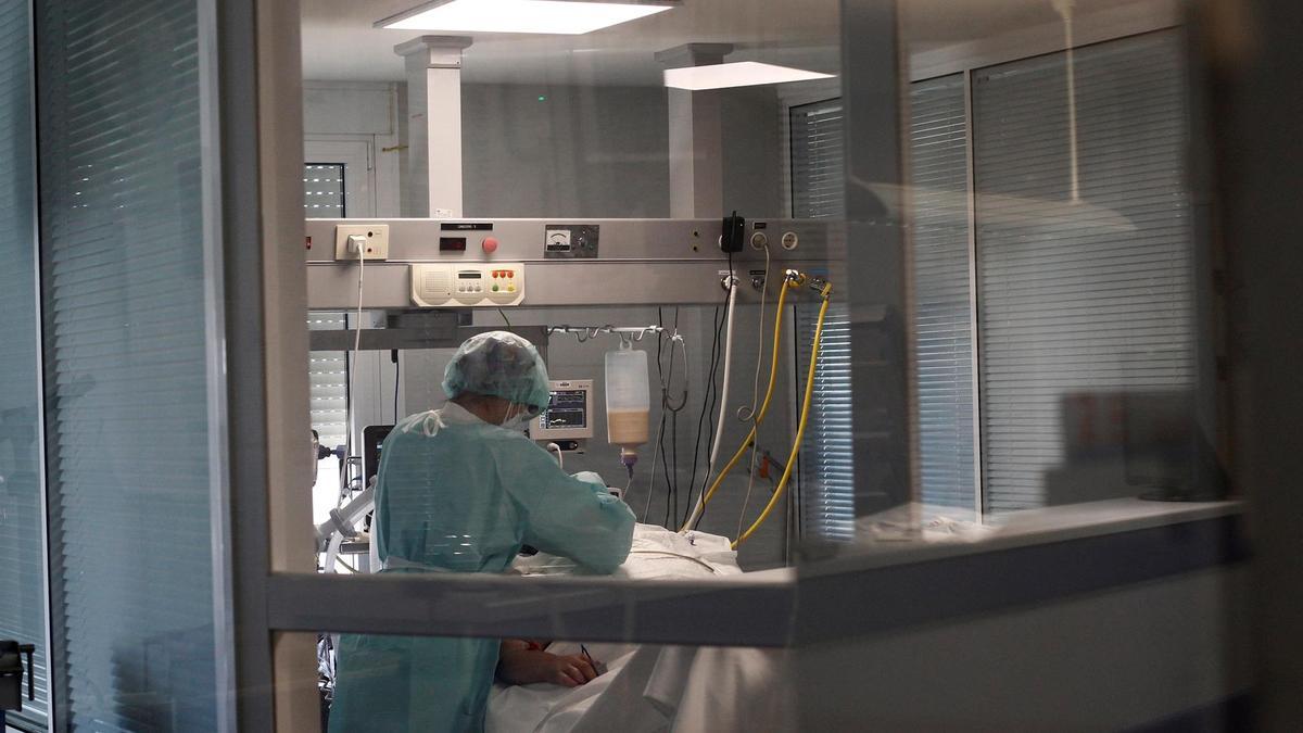Sanitaria atiende a paciente en el interior de la UCI de un hospital.