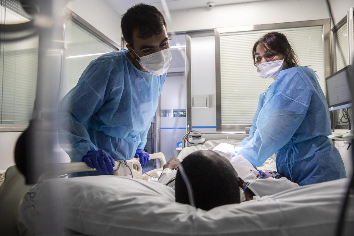 Dos sanitarios atienden a un ingresado en la UCI del Hospital Clínic (22 de julio 2022)