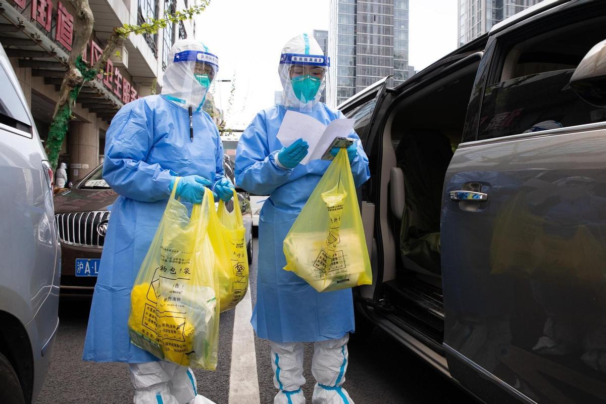 Dos personas con trajes EPI en el centro de Sanghái.
