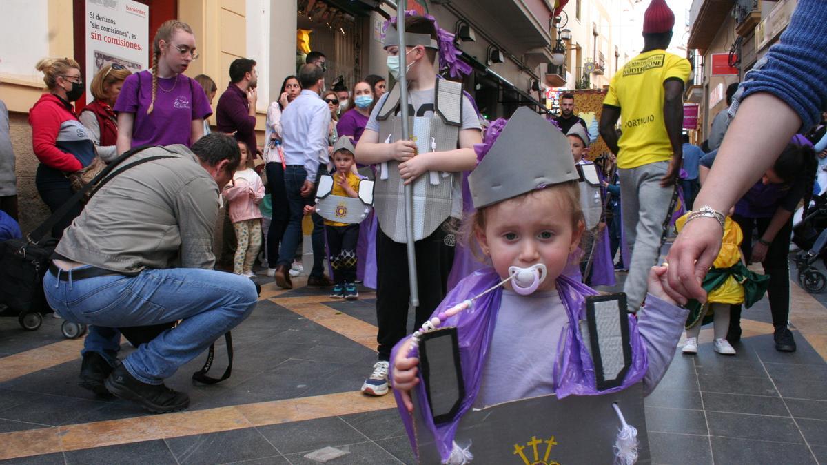 Una niña con chupete vestida de mayordomo anunciaba la llegada del cortejo del Paso Morado.