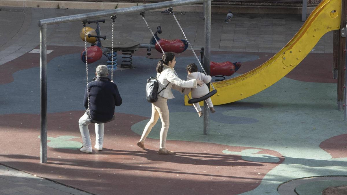 Una familia alzireña juega en el parque de la plaza Mayor.