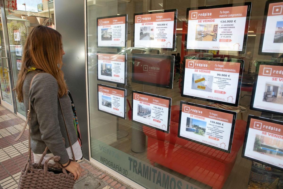 Una mujer observa los precios de los pisos en una inmobiliaria de Castelló.