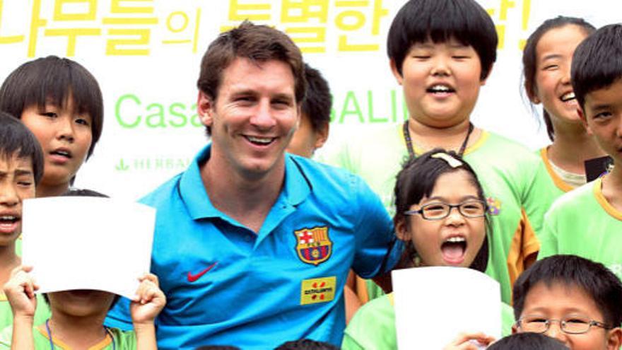 Messi sonríe mientras posa para los fotógrafos rodeado de un grupo de niños que juegan al fútbol en un hotel de Seúl