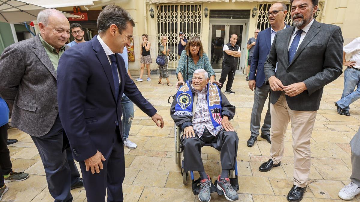 Rafael García Ripoll, en la silla, en la plaza de la concatedral de San Nicolás junto al alcalde Luis Barcala.