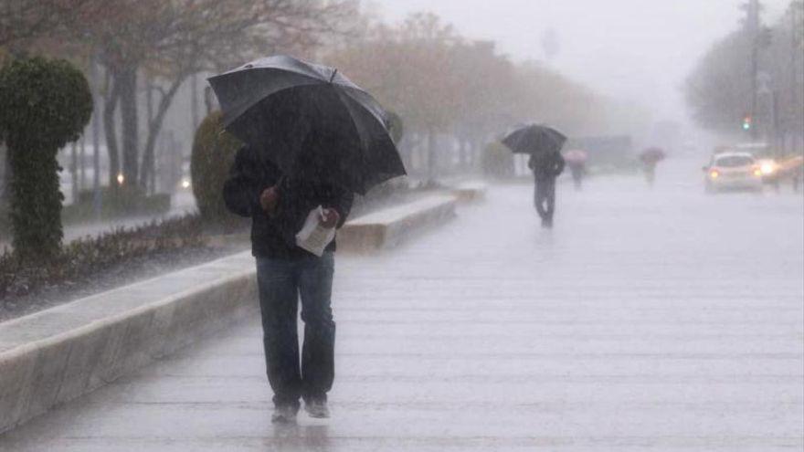 Un hombre se protege de la lluvia en el Vial de Córdoba.