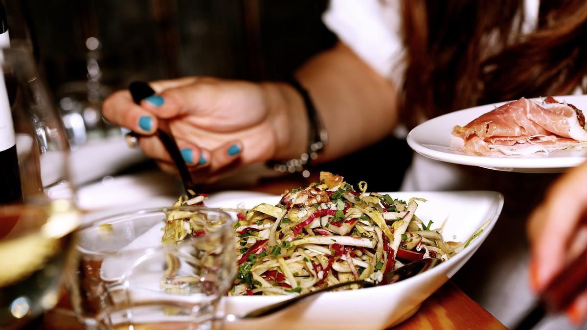 Una persona come una ensalada en un restaurante en una imagen de archivo