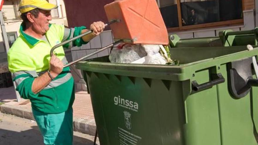 Foto de archivo de un operario del servicio de basuras arrojando desechos al contenedor.