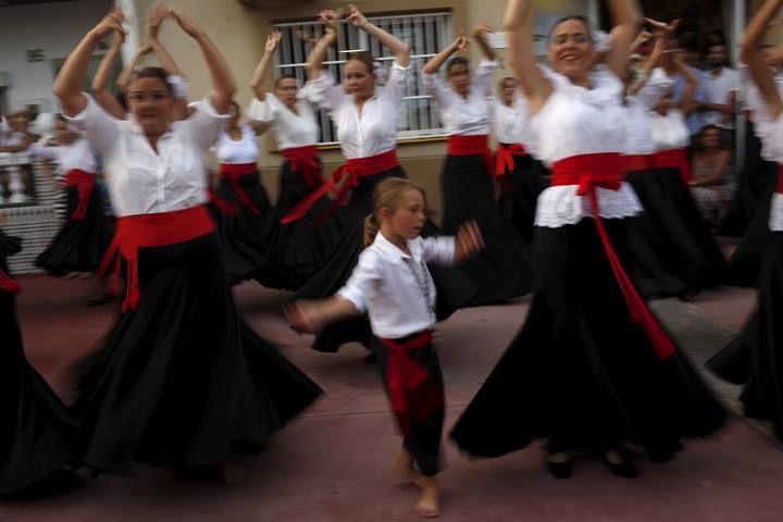 People in traditional costumes dance as they take part in the procession of the El Carmen Virgin being carried into the sea in Malaga