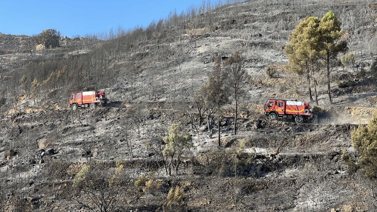 Los bomberos llevan a cabo trabajos de liquidación y refresco el lunes en terrenos afectados por el fuego en les Useres. | EFE