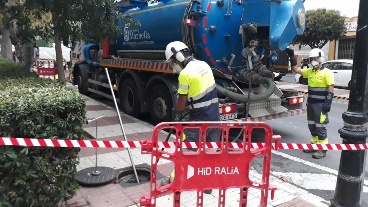 Dos operarios limpian una de las alcantarillas del municipio.