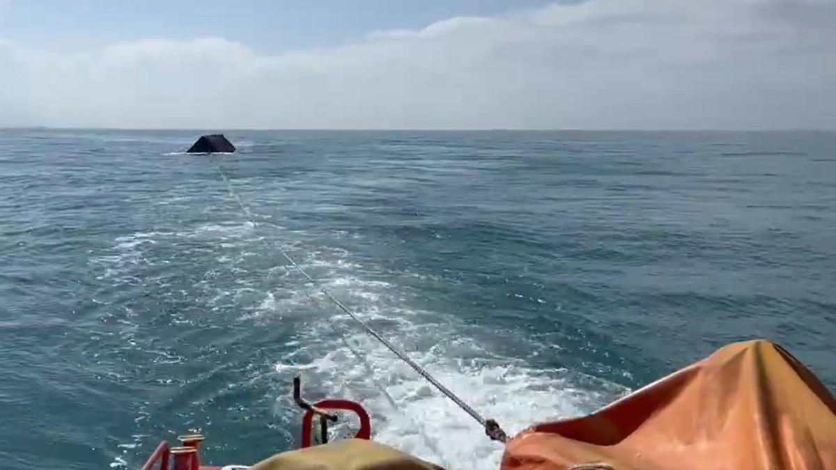Un barco remolca otro contenedor a la deriva en aguas de Cádiz.