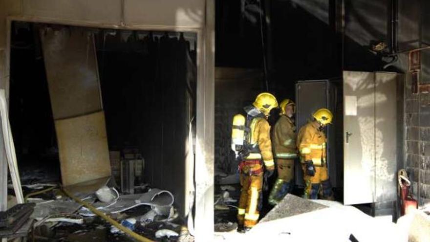 Imagen del interior destrozado por las llamas. A la derecha, los bomberos frente a la nave siniestrada ayer en Aspe.