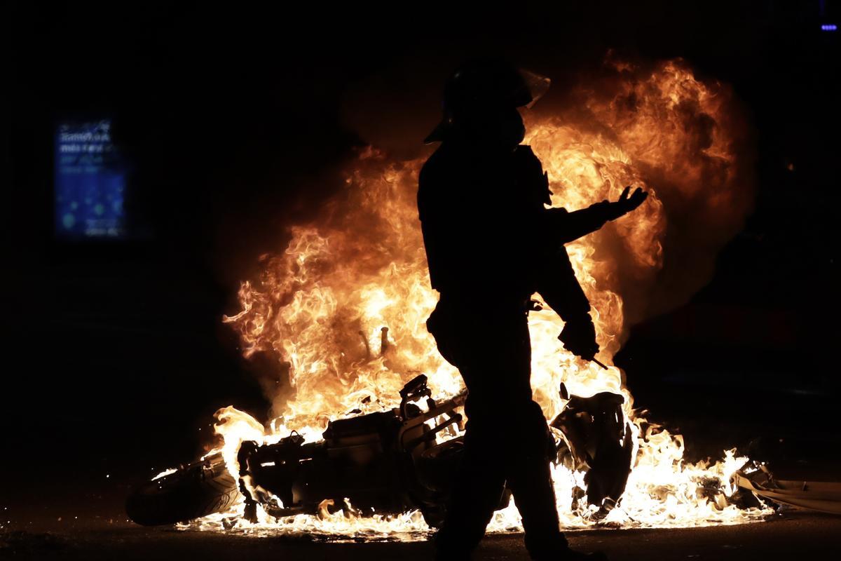 Un mosso d’Esquadra, ante una moto en llamas durante las protestas por la prisión de Pablo Hasél. 