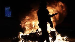 Un mosso d’Esquadra, ante una moto en llamas durante las protestas por la prisión de Pablo Hasél. 