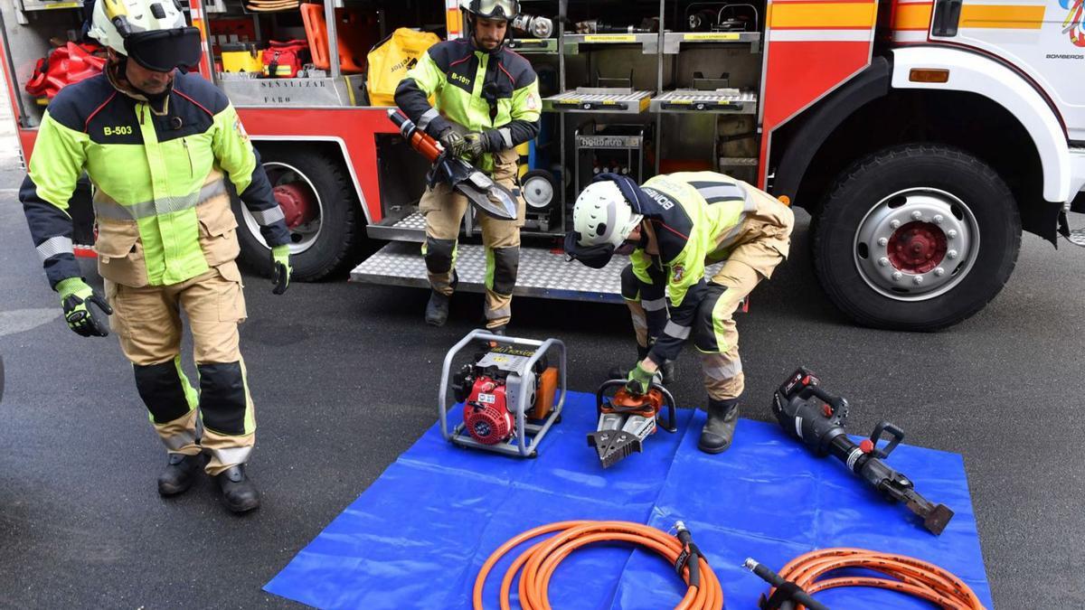 Uno de los bomberos abre la puerta de un coche con una de las máquinas de excarcelación con batería.   | // VÍCTOR ECHAVE