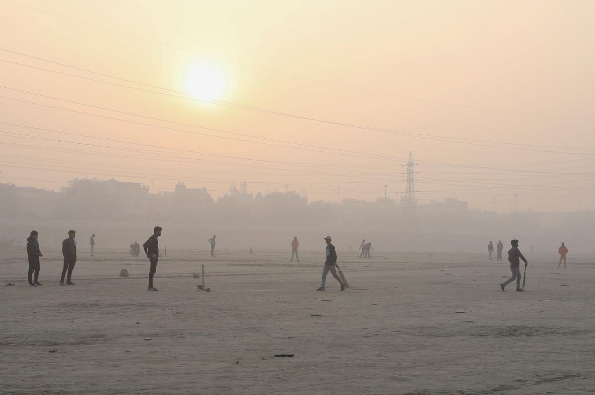 Gente jugando al cricket en una llanura junto al río Yamuna en una mañana con abundante ’smog’ en Nueva Delhi.