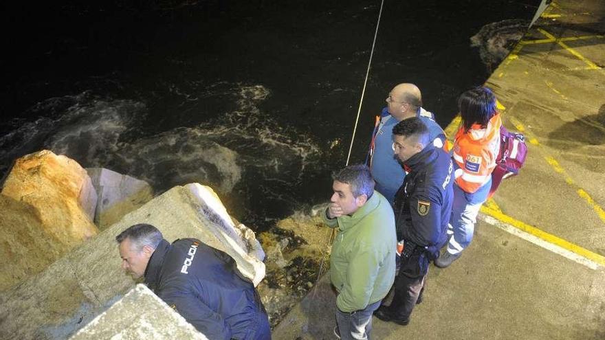 Agentes de la Policía Nacional, sanitarios y un pescador, ayer, en O Portiño. víctor echave