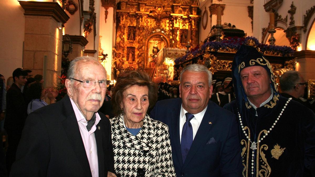 Ante el trono de la Buena Muerte posaba junto a su esposa, al presidente del Paso Azul y al Hermano Mayor del Yacente.