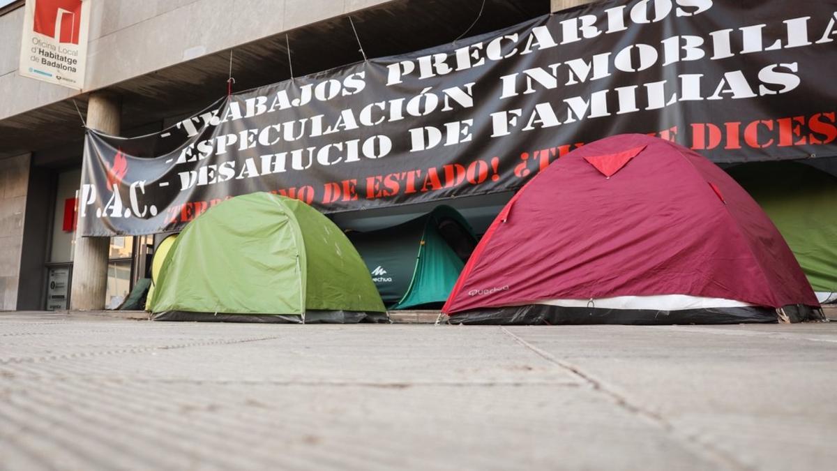 El campamento constituido por tiendas de campaña y sillas de plástico delante de la Oficina de Vivienda