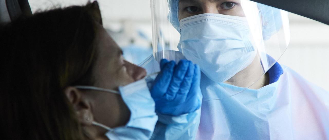 Una sanitaria le realiza la prueba PCR a una mujer en su coche durante la realización de PCR en el autocovid instalado en el Hospital Militar, a 28 de diciembre de 2021 en Sevilla (Andalucía, España)