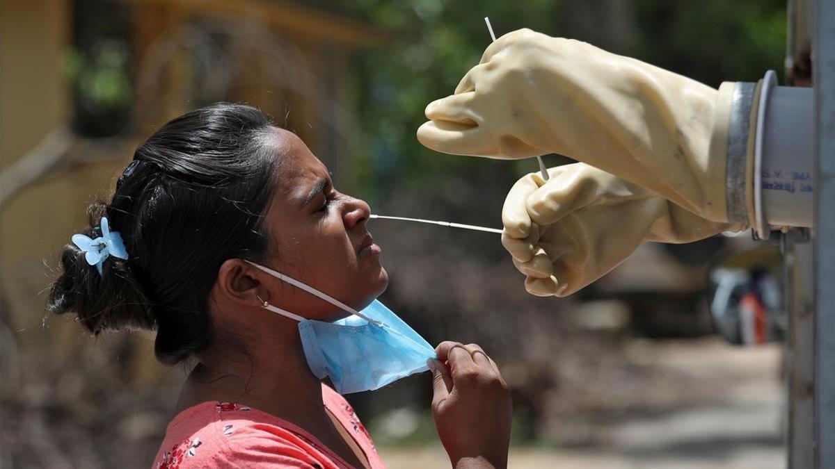 Un sanitario realiza la prueba del covid-19 a una mujer en Kolkata (India).