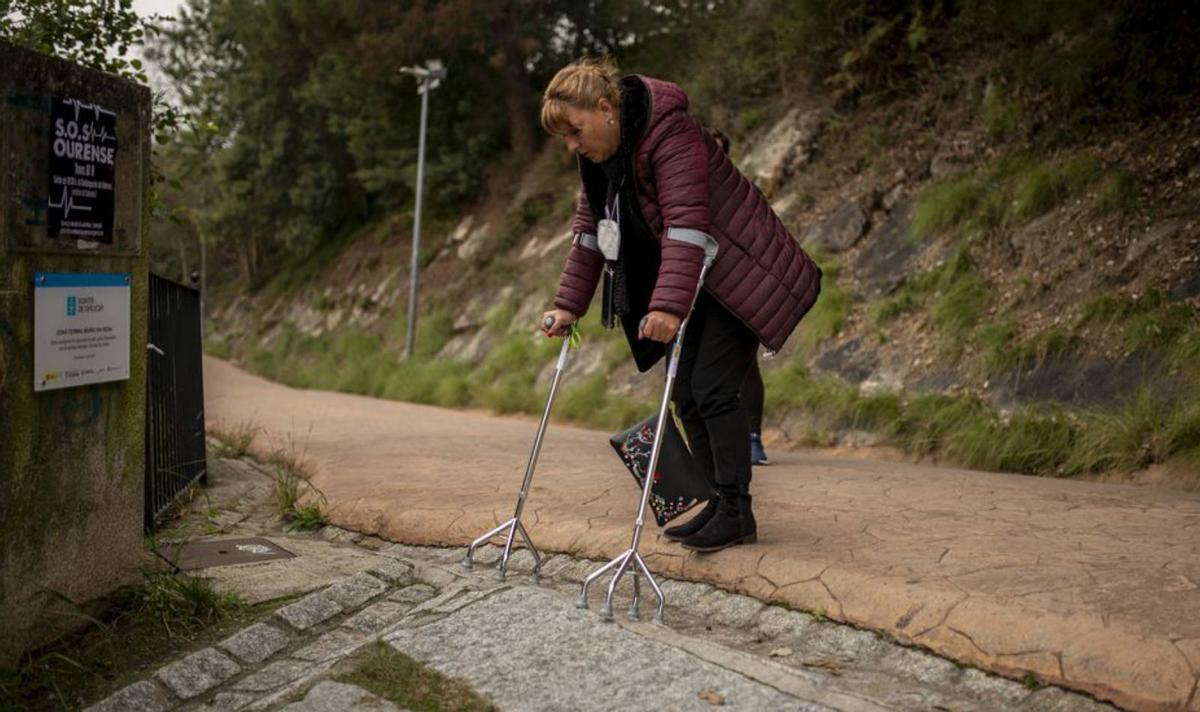 Con las muletas y con pausas baja la pendiente hacia el río. | // BRAIS L.