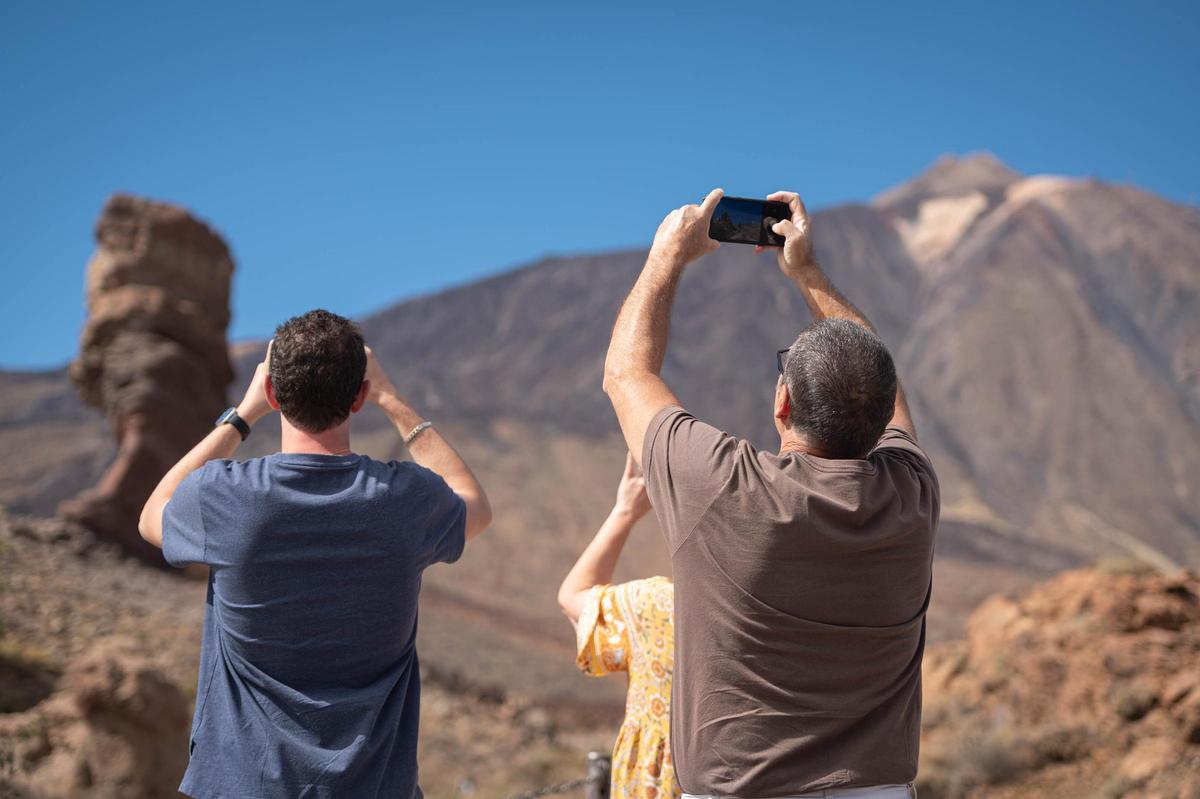 Tres turistas toman fotos del Teide en el parque nacional tinerfeño.