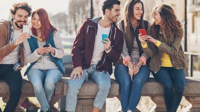 Un grupo de jóvenes relacionandose entre si e interactuando con sus móviles.