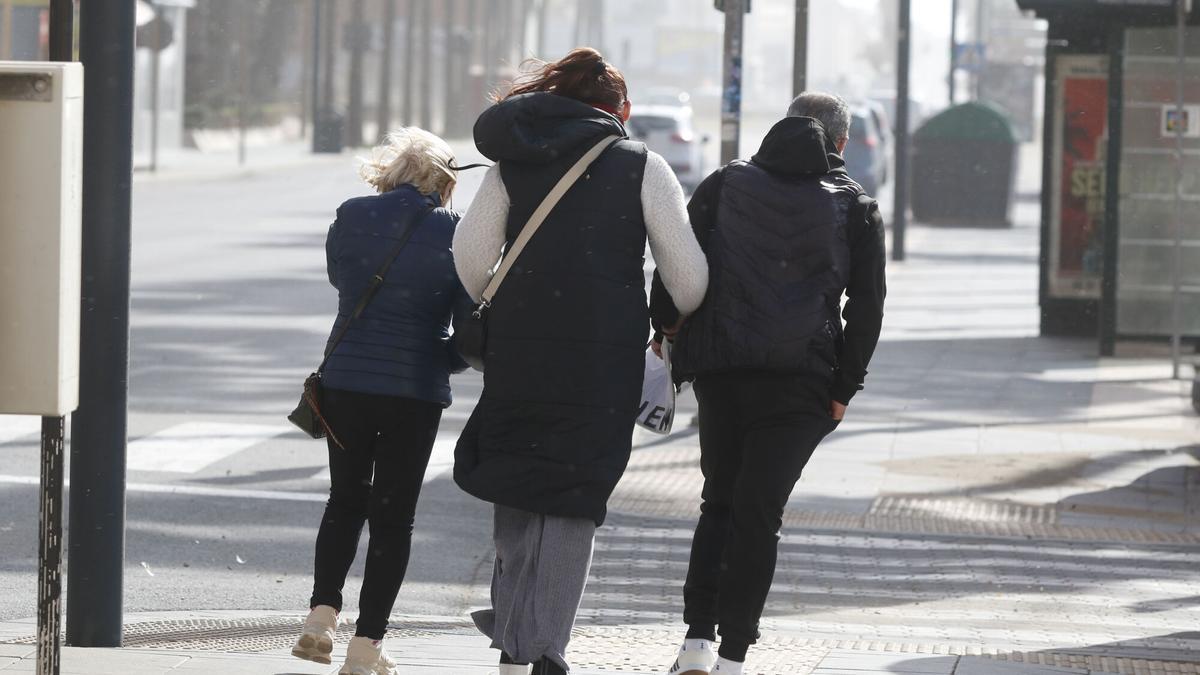 Varias personas caminan entre el fuerte viento que se registra en Almería.