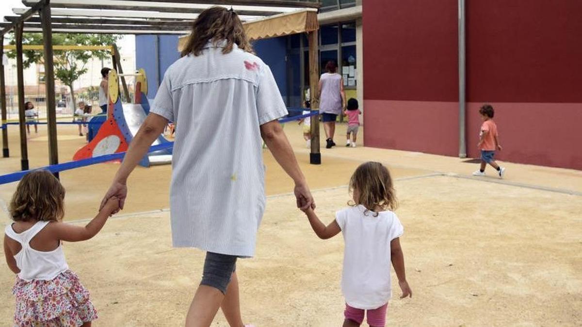 Una maestra de Infantil acompaña guía a dos niñas a su aula.