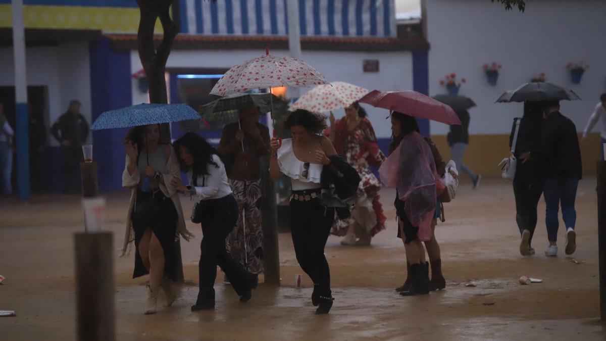 Varias personas bajo la lluvia este martes por la tarde-noche en la Feria de Córdoba.