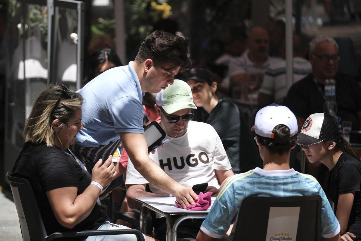 Un camarero sirve una mesa en una terraza.