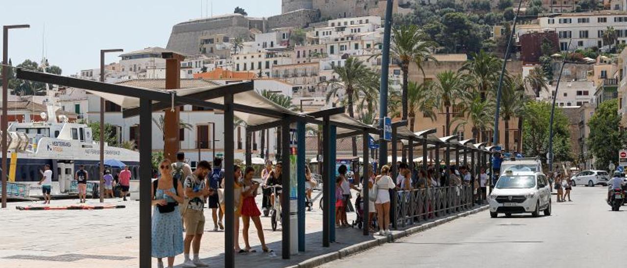 Usuarios del taxi esperan a la sombra en la avenida de Santa Eulària. | TONI ESCOBAR