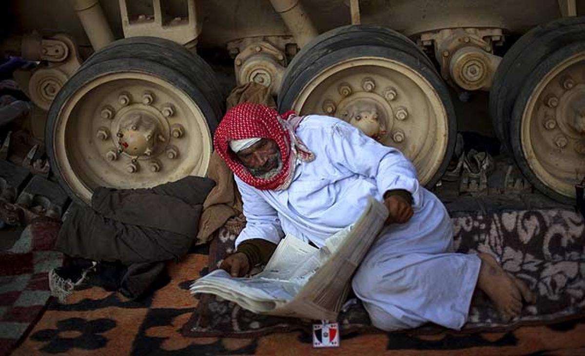 Un manifestant anti-Mubàrak llegeix el diari al costat d’un tanc de l’Exèrcit a prop de la plaça Tahrir al Caire (Egipte).