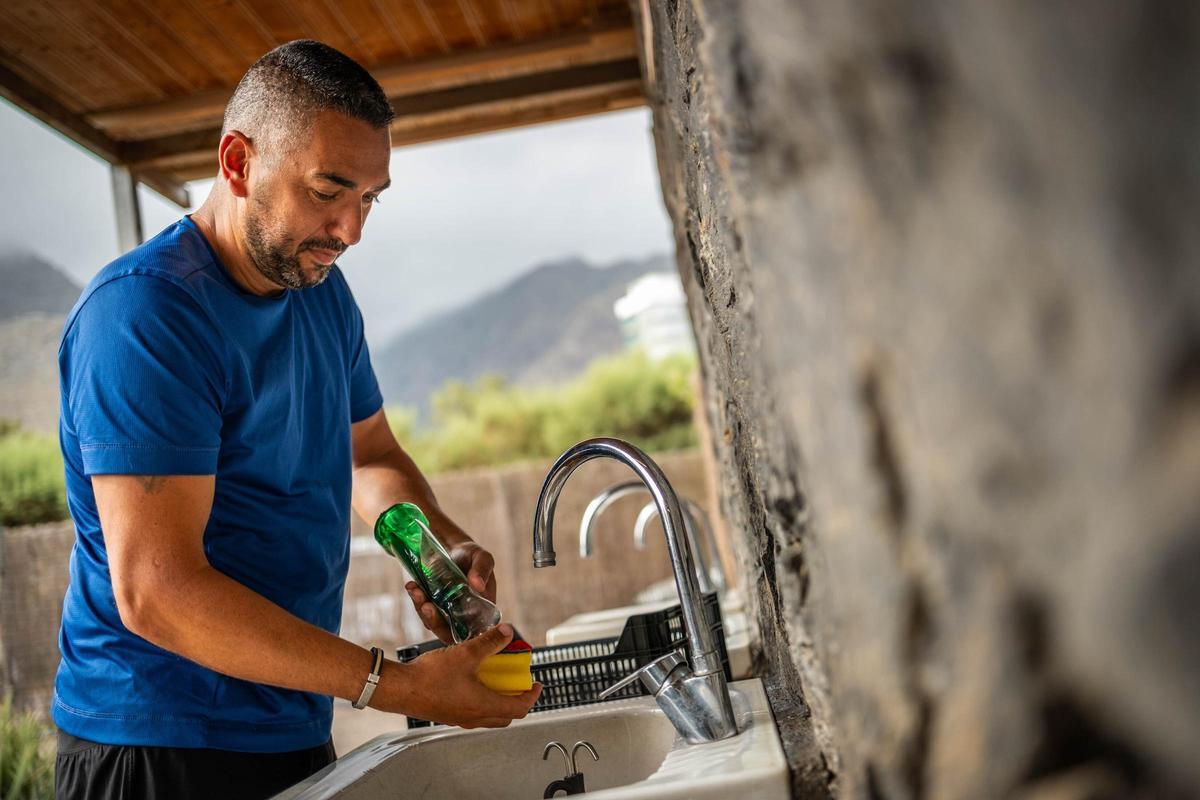 Jonay Siberio, usuario del camping, limpiando la vajilla utilizada en el desayuno