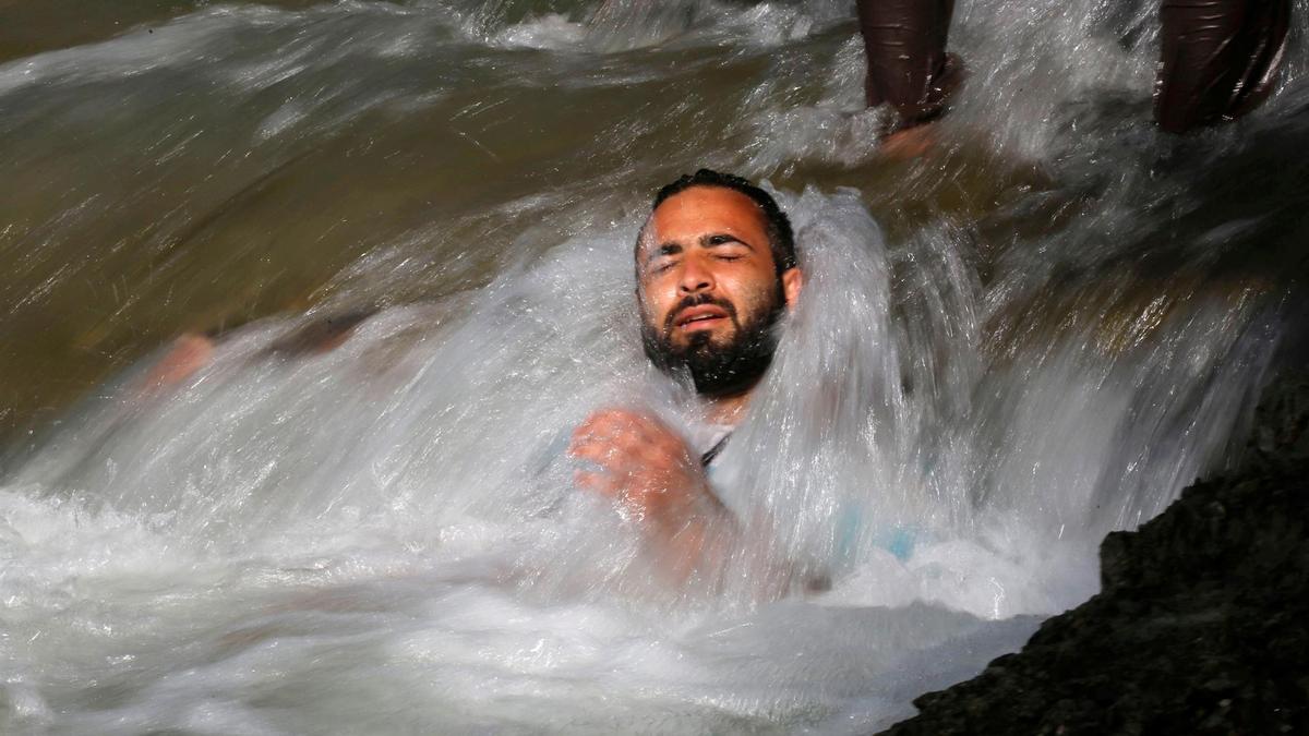 Un hombre se refresca bajo una cascada