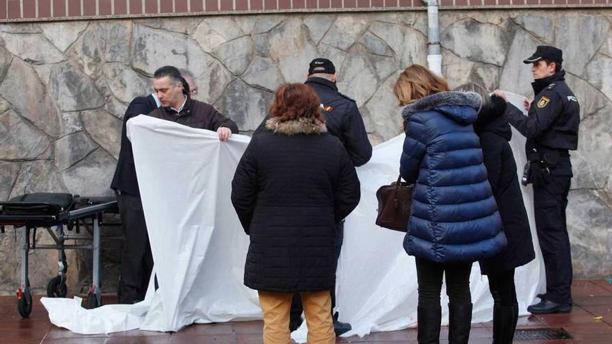 Varios agentes de la Policía tapan el cuerpo de la fallecida tras precipitarse desde la ventana de su domicilio.