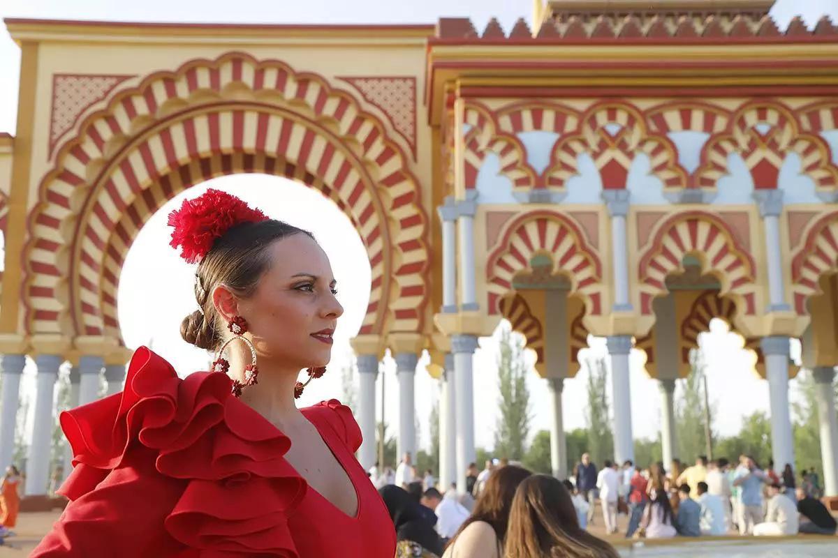 Una mujer con traje de gitana junto a la portada de la Feria de Córdoba, en la pasada edición de 2025.