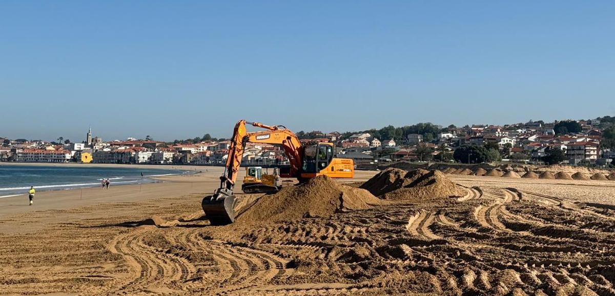 Una excavadora retira arena para depositarla en la desembocadura del río Muíños y recuperar la duna. | FDV