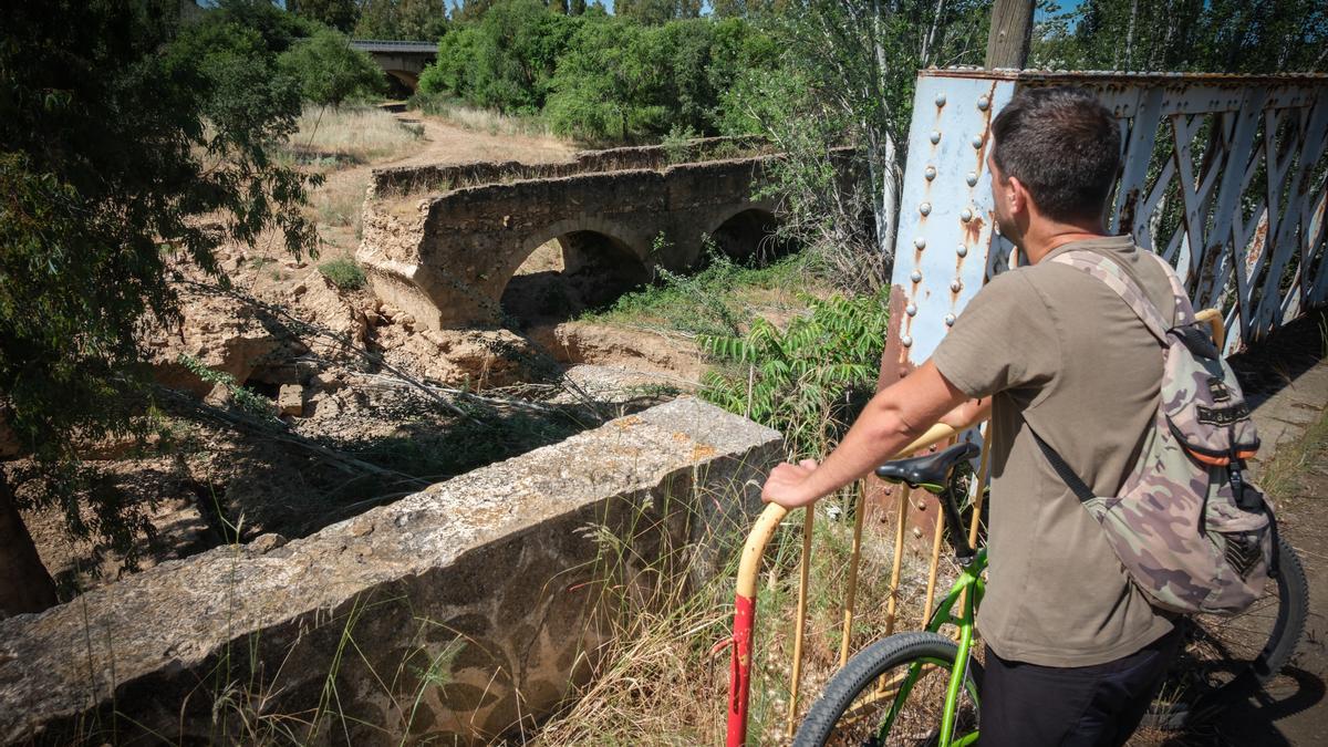 Un ciclista observa el puente de Cantillana, parcialmente derruido.