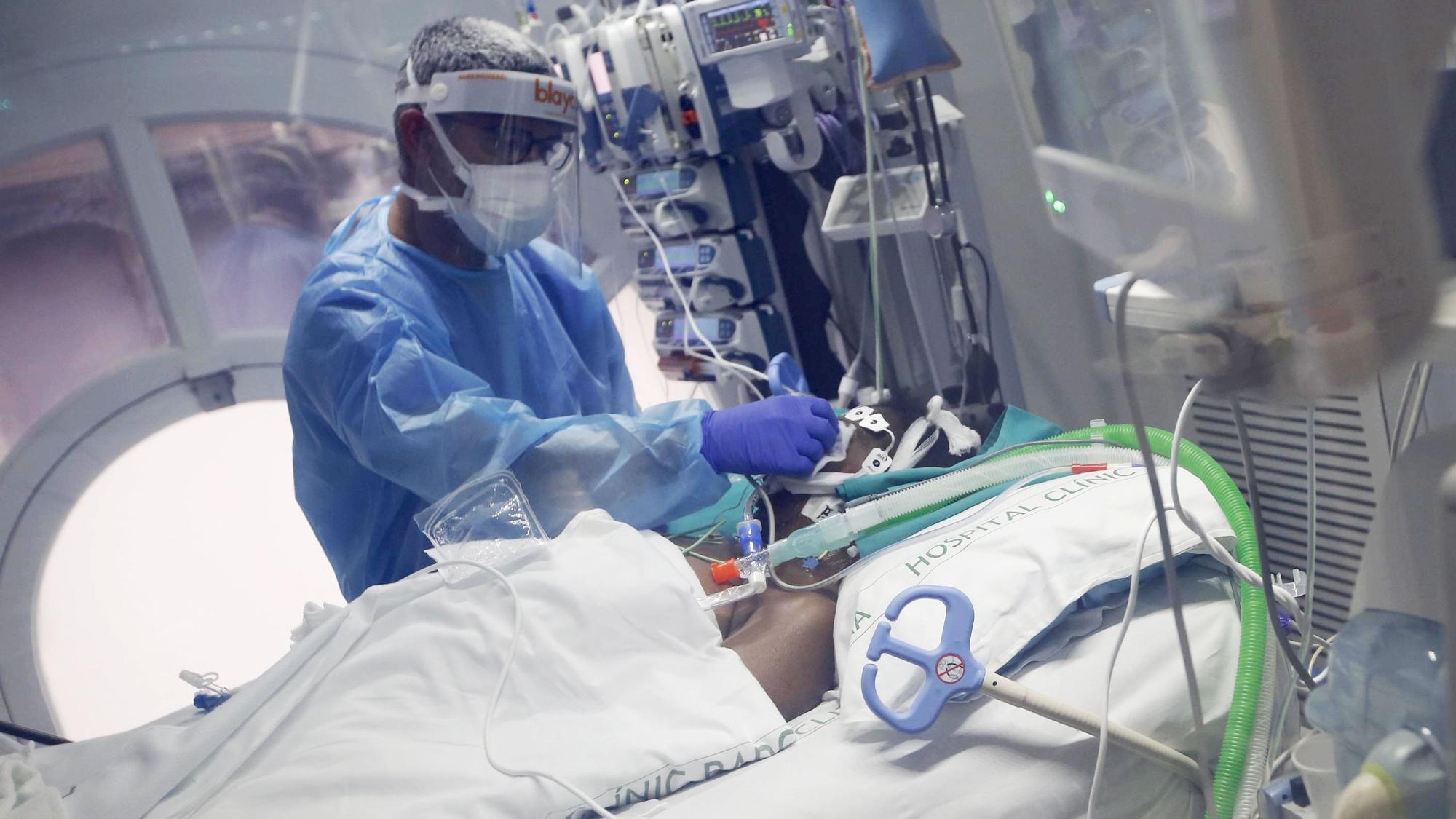 Un medico asiste a un enfermo de covid-19, en la UCI del Hospital Clínic de Barcelona, hoy.