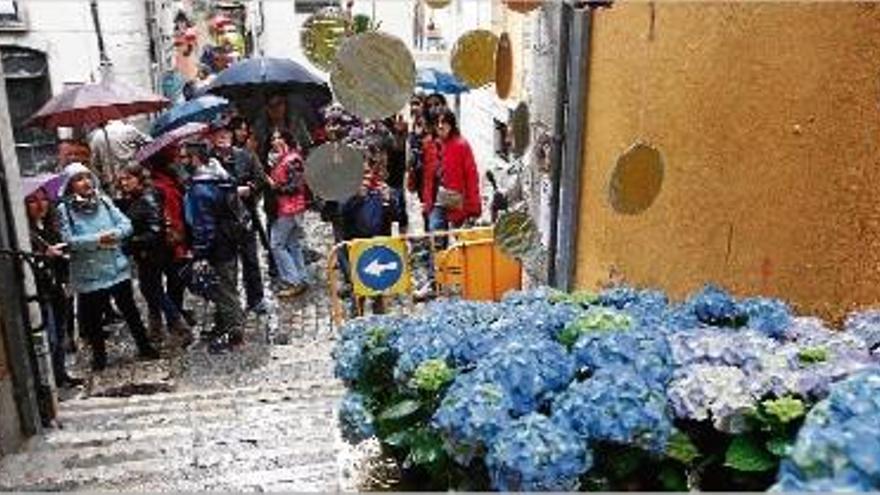 Visitants al Barri Vell de Girona, suportant les inclemències meteorològiques.