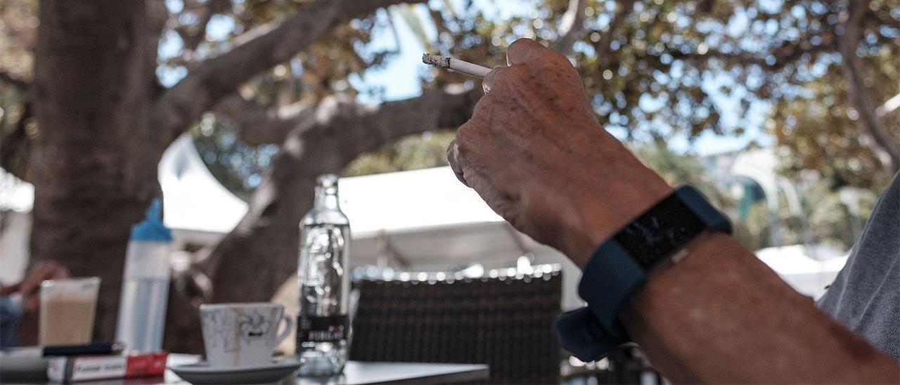 Un hombre fuma en una terraza.