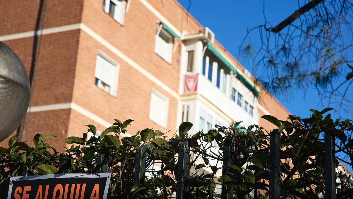 Un cartel anuncia alquiler ante un edificio de viviendas