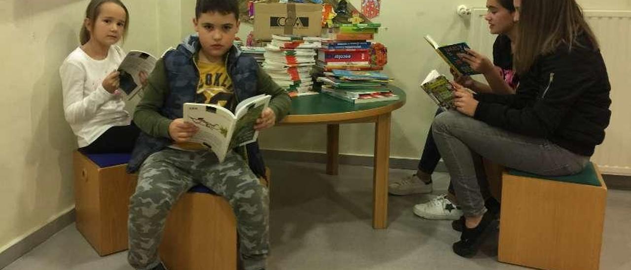 Julia Fernández, Mateo Redondo, Olaya Fernández y Beatriz Fernández hojean los nuevos libros de la sección infantil y juvenil donados por el presidente de Anaya a la biblioteca de Infiesto, ayer.