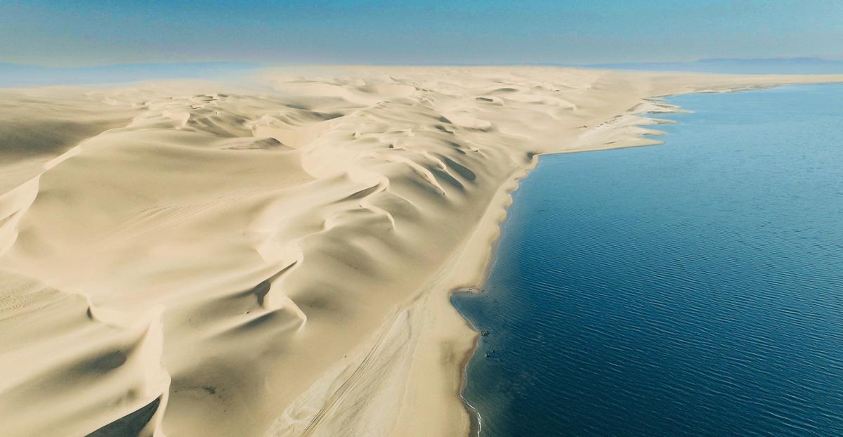 Vista aérea del encuentro de las dunas y el océano en la Costa de los Esqueletos desde el lado angoleño.